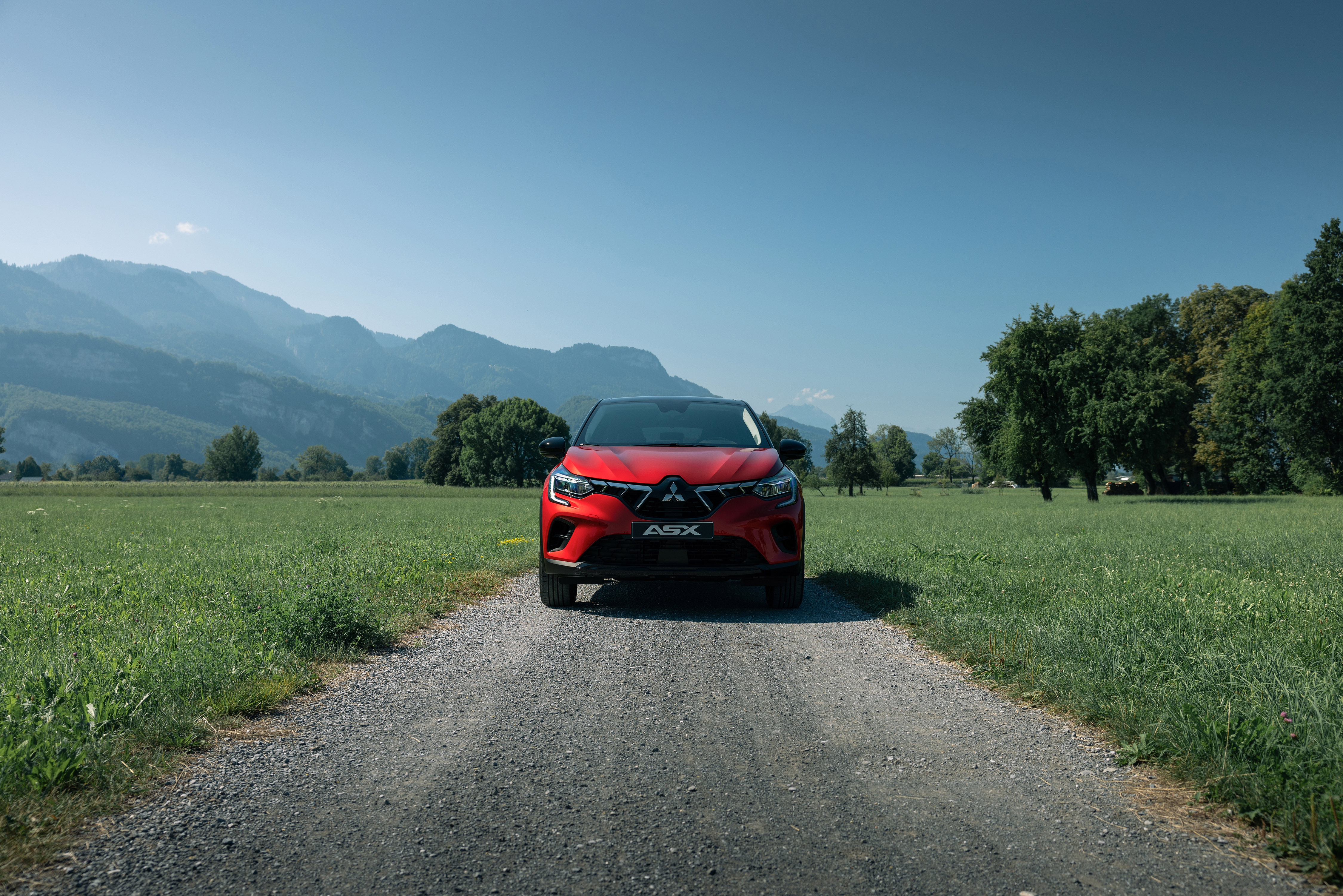 Rode Mitsubishi ASX op weg tussen grasvelden