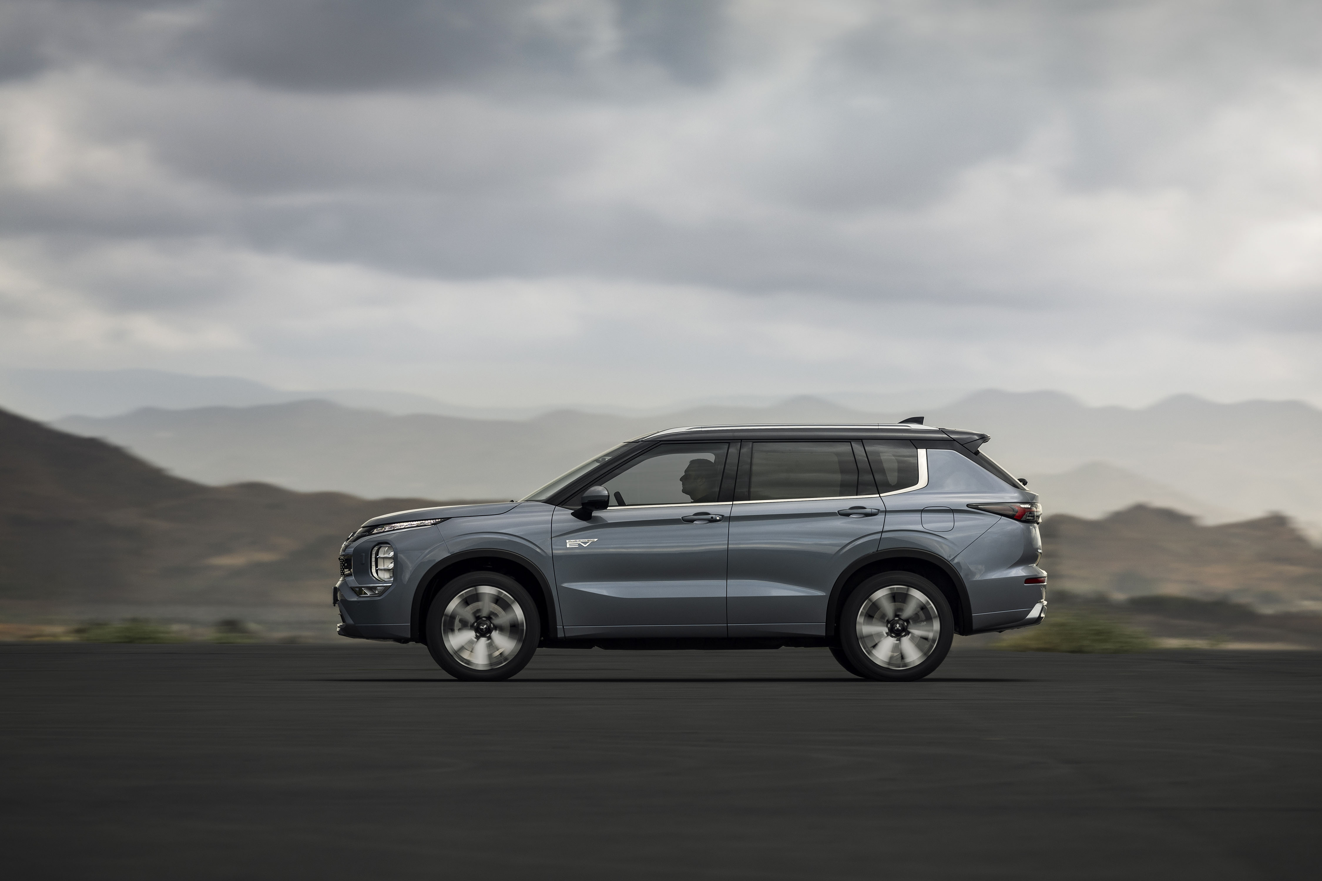 Mitsubishi Outlander PHEV MY2025 in woestijn met wolkenlucht