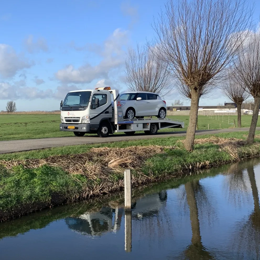 Oprijwagen Autobedrijf Van Zessen met auto in de polder op een mooie januaridag met een blauwe lucht en een paar kleine wolken
