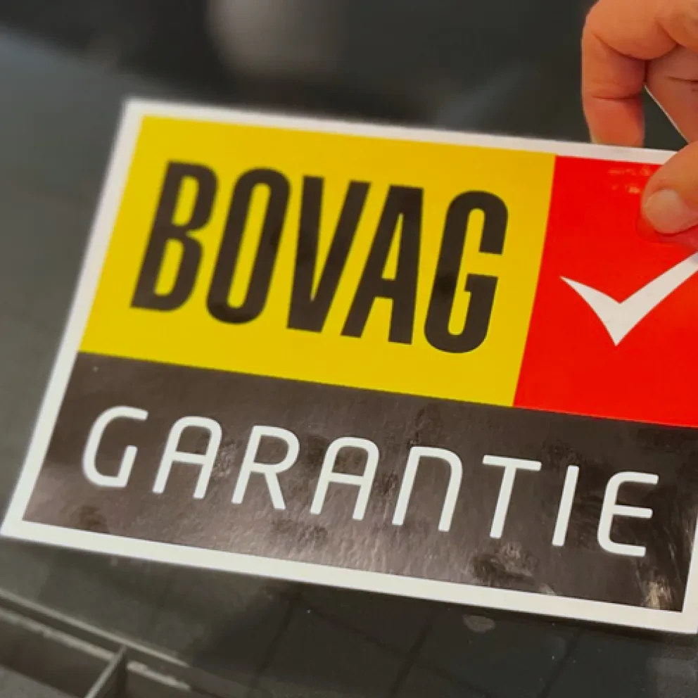 Sticker BOVAG garantie wordt op autoruit geplakt