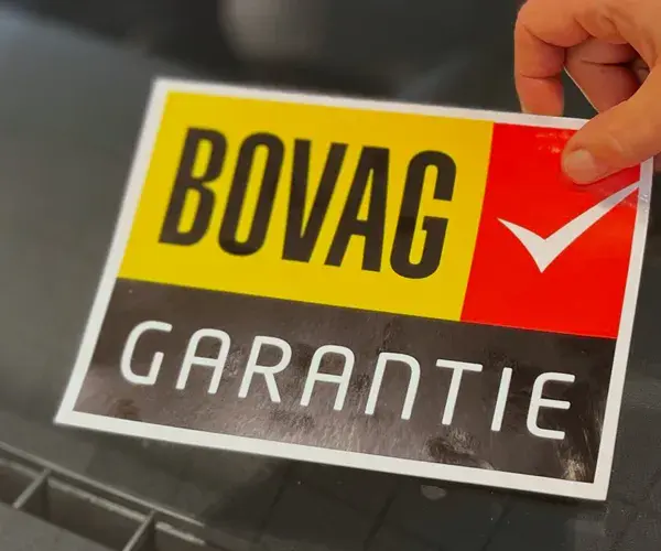 Sticker BOVAG garantie wordt op autoruit geplakt