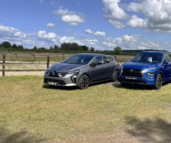 Mitsubishi Colt Volcanic Grey Mitsubishi Eclipse Cross PHEV Lightning Blue en Peugeot Partner grijs metallic op grasveld met hollandse wolkenlucht