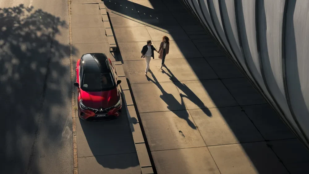 Rode Mitsubishi ASX op openbare weg met mensen op het trottoir