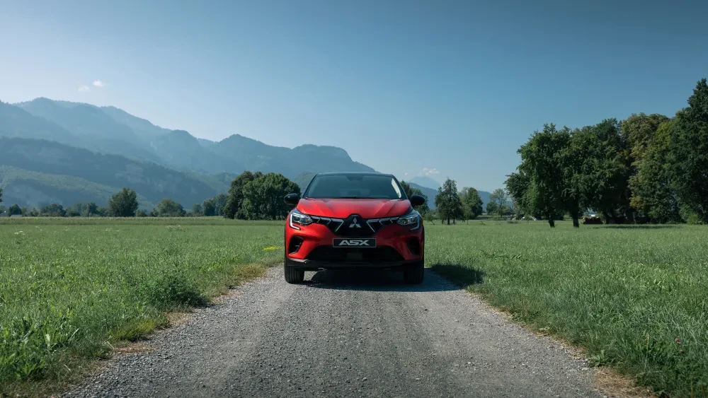 Rode Mitsubishi ASX op weg tussen grasvelden