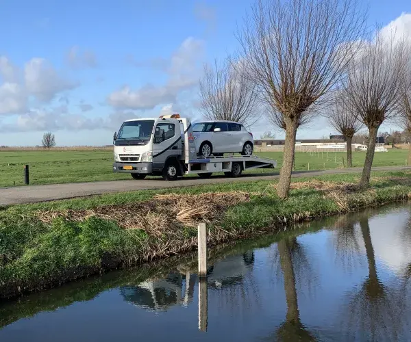 Oprijwagen Autobedrijf Van Zessen met auto in de polder op een mooie januaridag met een blauwe lucht en een paar kleine wolken